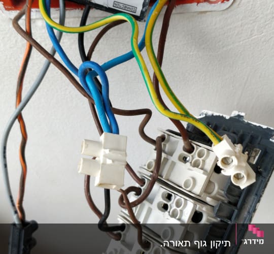 חוטי חשמל מחוברים למתג בקיר פתוח